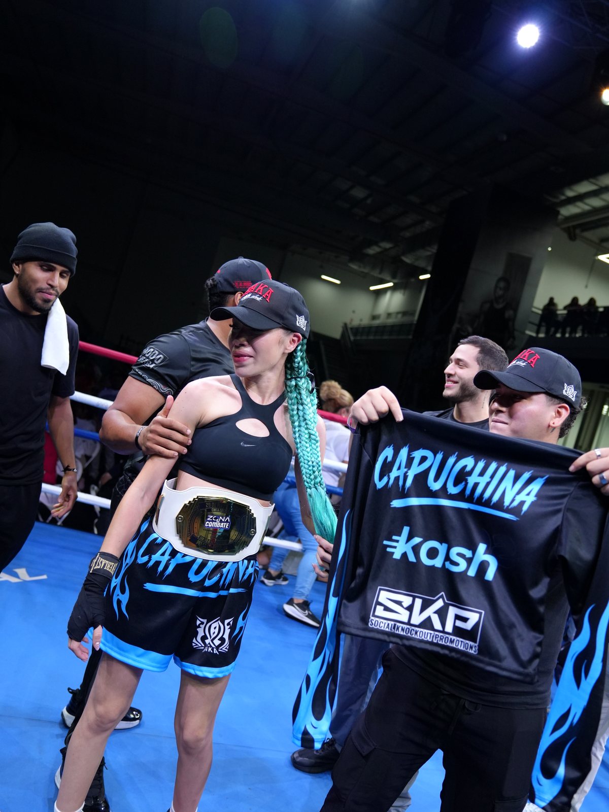 Campeona con el cinturón rodeada de su equipo